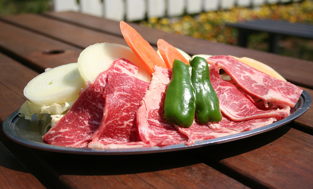 皿の上にバーベキューの材料である生の牛肉や生野菜がのっている画像
