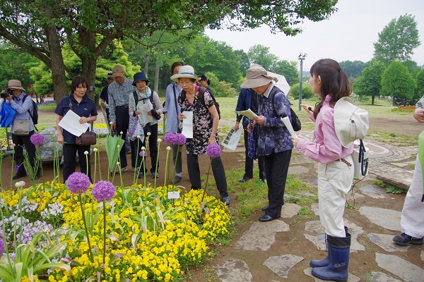 園内で見頃を迎える植物をスタッフが案内している様子