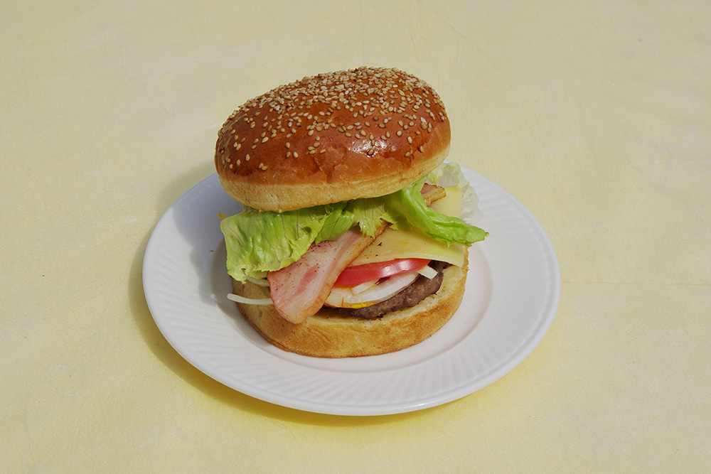 レタスベーコントマトが挟まれたハンバーガーの画像